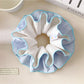 Blue double layer scrunchie wrapped around a ponytail