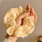 Yellow and white striped scrunchie wrapped around a ponytail