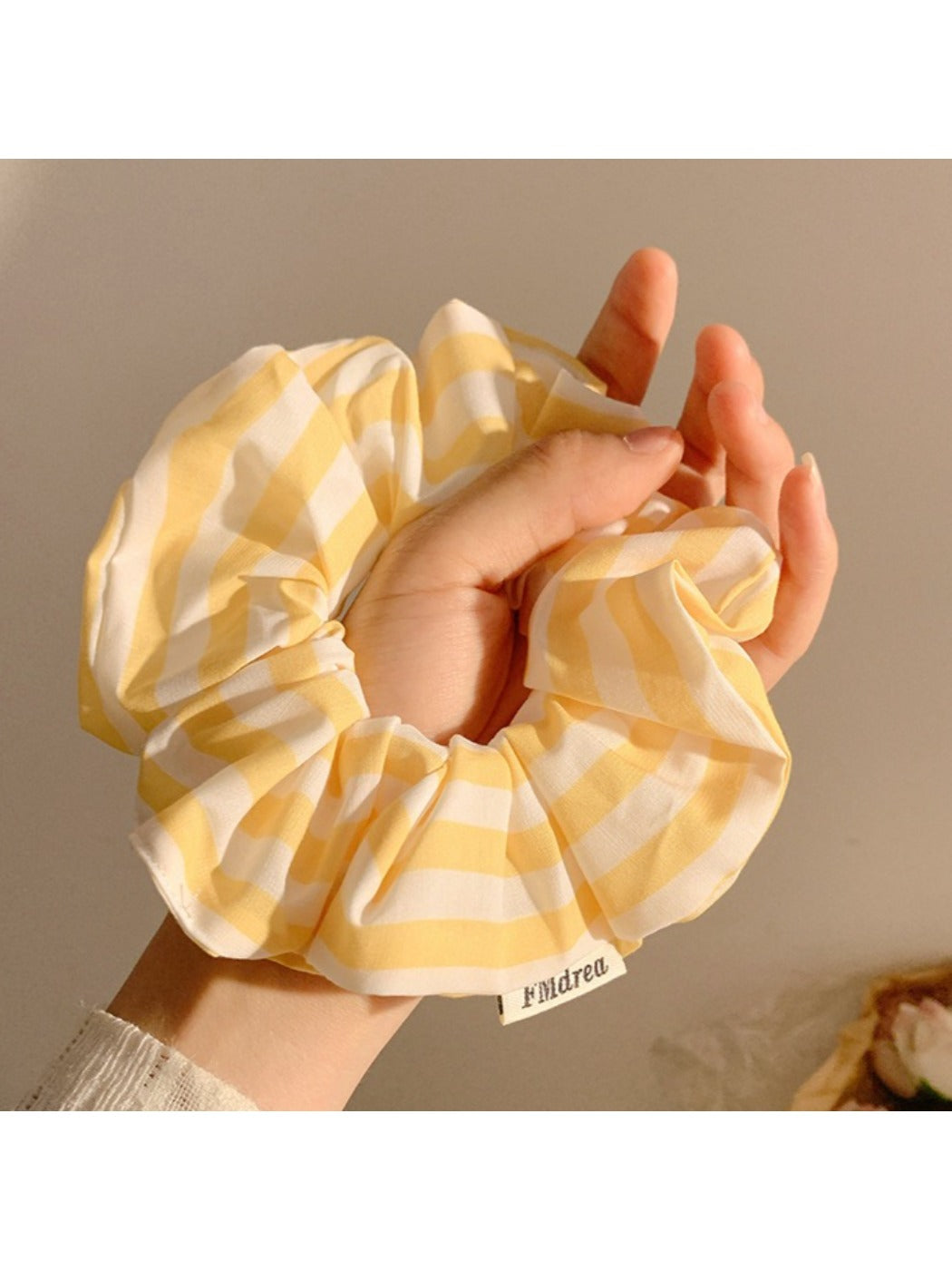 Yellow and white striped scrunchie wrapped around a ponytail