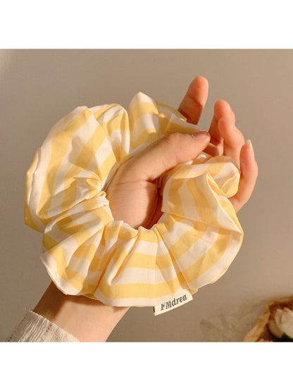 Yellow and white striped scrunchie wrapped around a ponytail