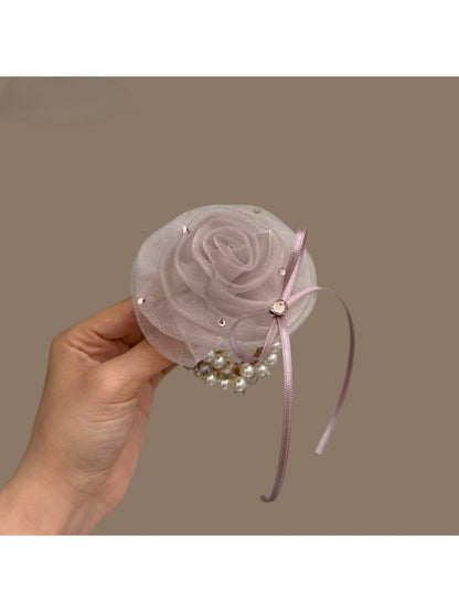 Hair tie worn on wrist displaying white flower decoration and black elastic
