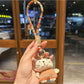 Silver cat charm keychain attached to a set of keys on a wooden surface