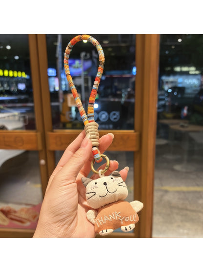 Silver cat charm keychain attached to a set of keys on a wooden surface