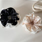 Beige satin scrunchie with delicate lace trim on a white background