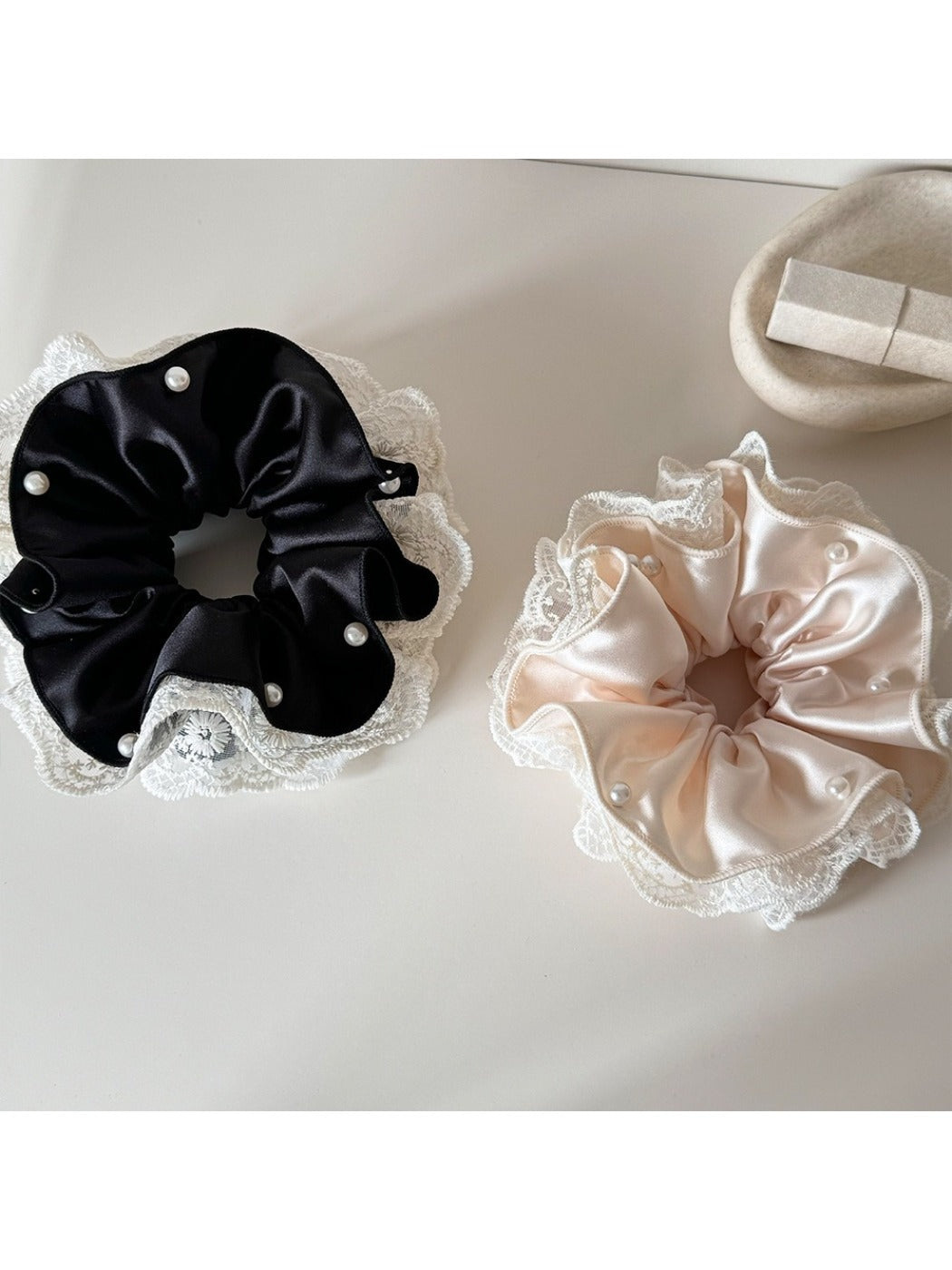 Beige satin scrunchie with delicate lace trim on a white background