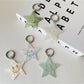 Silver star pendant keychain attached to a set of keys on a wooden surface