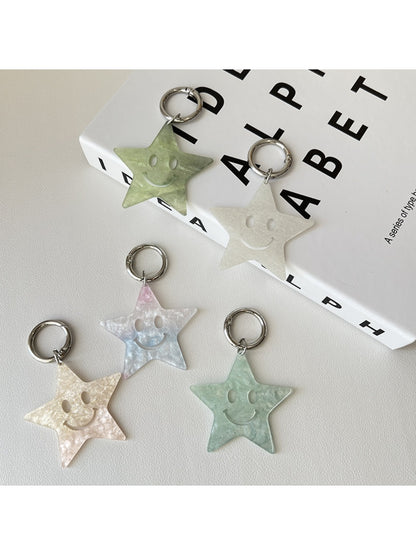 Silver star pendant keychain attached to a set of keys on a wooden surface