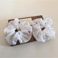 White flower scrunchie displayed flat showing gathered fabric details
