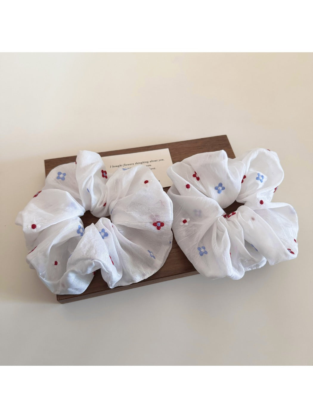 White flower scrunchie displayed flat showing gathered fabric details