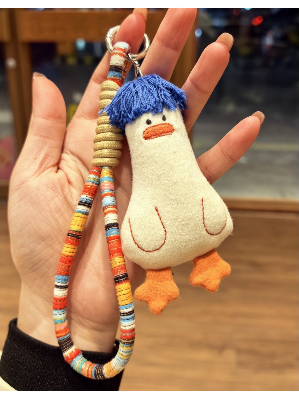 Blue duck keychain hanging from a bag zipper with visible hair strands
