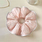 Pink striped hair scrunchie displayed on a wooden surface