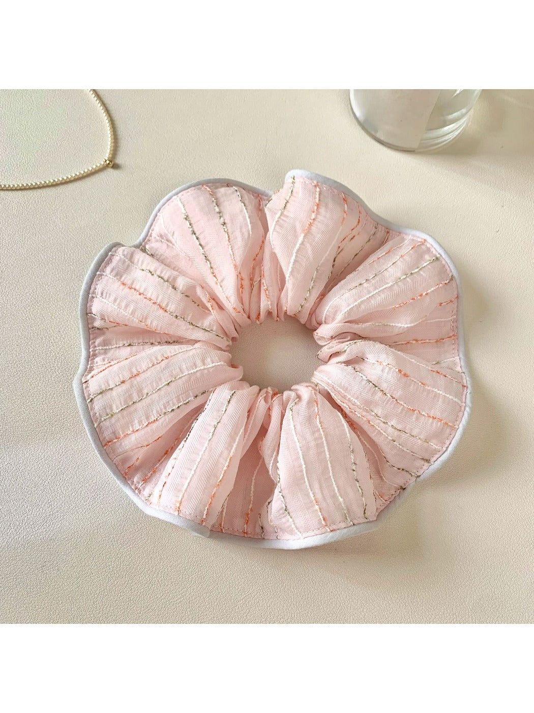 Pink striped hair scrunchie displayed on a wooden surface