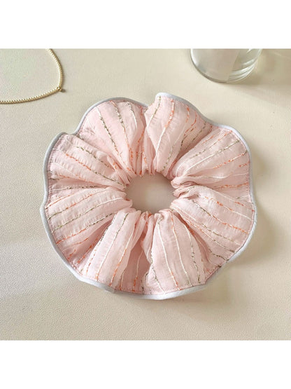 Pink striped hair scrunchie displayed on a wooden surface