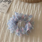 Scrunchie held in hand showing elastic stretch and floral design
