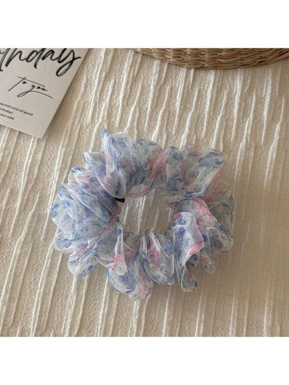 Scrunchie held in hand showing elastic stretch and floral design