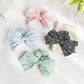 Chic striped bow scrunchie in beige and white fabric on a white background