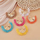 Close-up of Earedge raffia woven fan shape earrings on white background