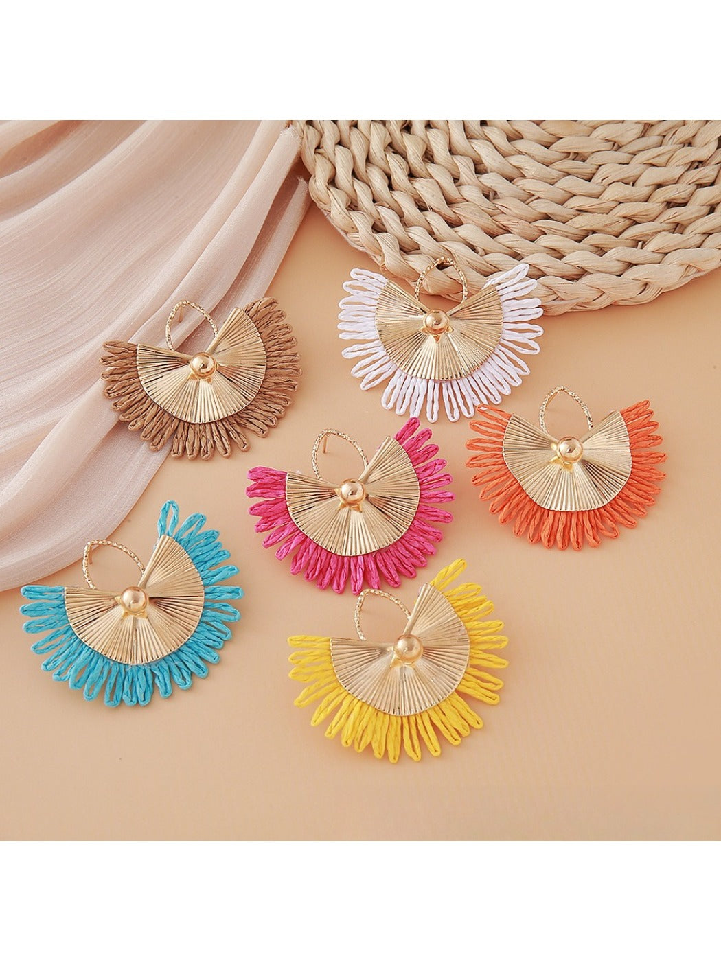 Close-up of Earedge raffia woven fan shape earrings on white background