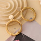 Side view of Earedge woven rattan round hollow earrings showing texture