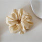 Gifty soft polka dot scrunchie in pastel pink held in hand against neutral background