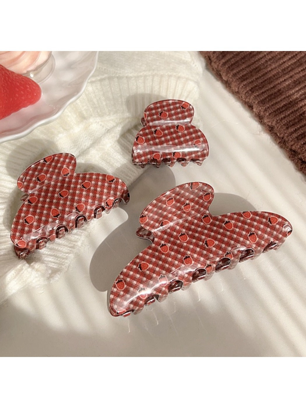 Beau hair claw clip open, displaying teeth and strawberry plaid fabric