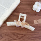 Beau large acetate claw clip resting on a wooden surface with natural light