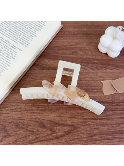 Beau large acetate claw clip resting on a wooden surface with natural light