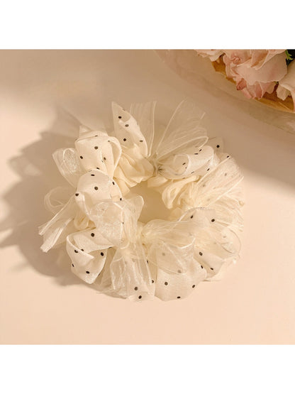 White polka dot tulle scrunchie displayed on a wooden surface