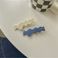 Beau hair clip open to reveal metal clasp mechanism and blue floral design