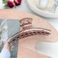 Pastel curved claw clip with curved design resting on marble background