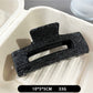 Beau black acetate claw clip worn in medium-length hair outdoors