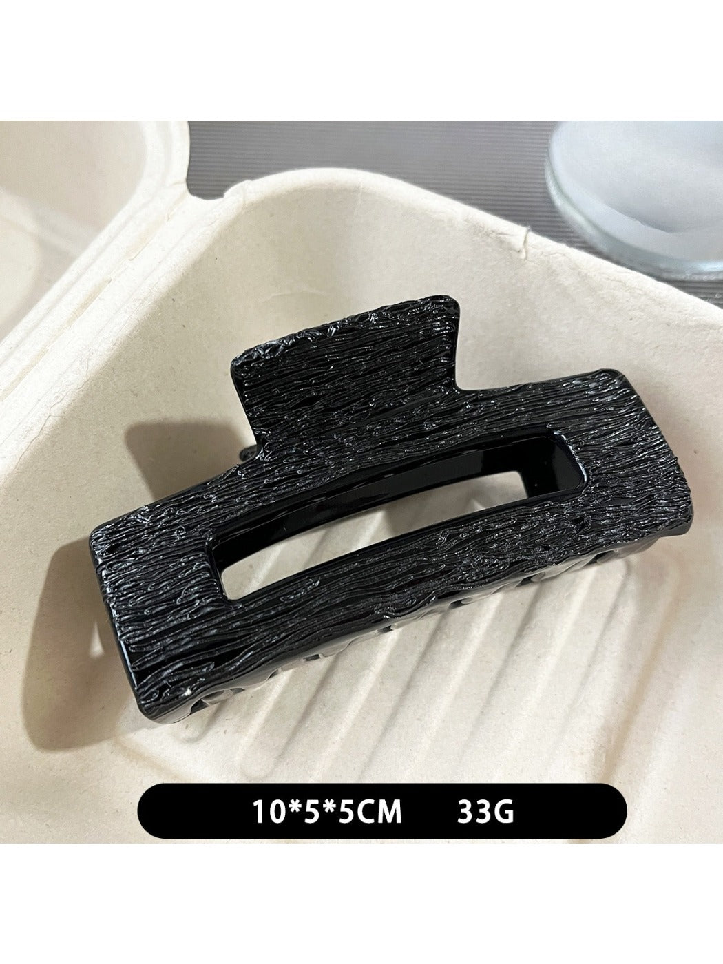 Beau black acetate claw clip worn in medium-length hair outdoors