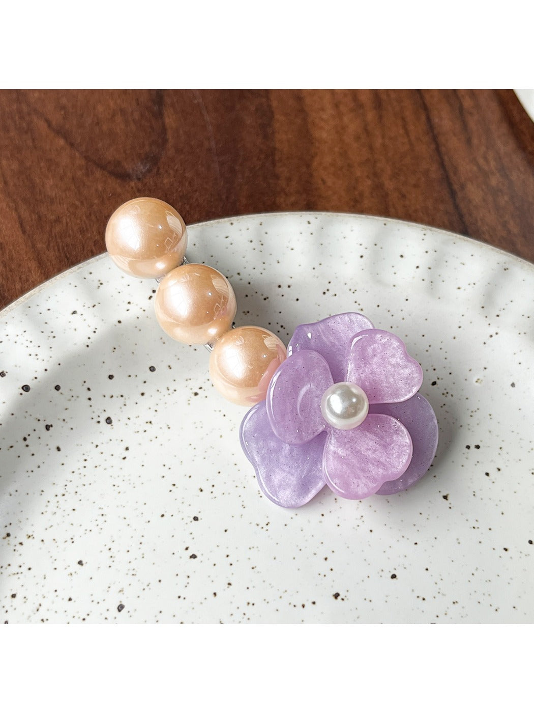 Beau Camellia shaped hair clip with white beads against a dark background