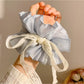 Close-up of Gifty pink bow scrunchie showing fabric texture and bow detail