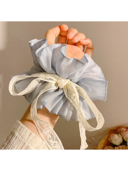 Close-up of Gifty pink bow scrunchie showing fabric texture and bow detail