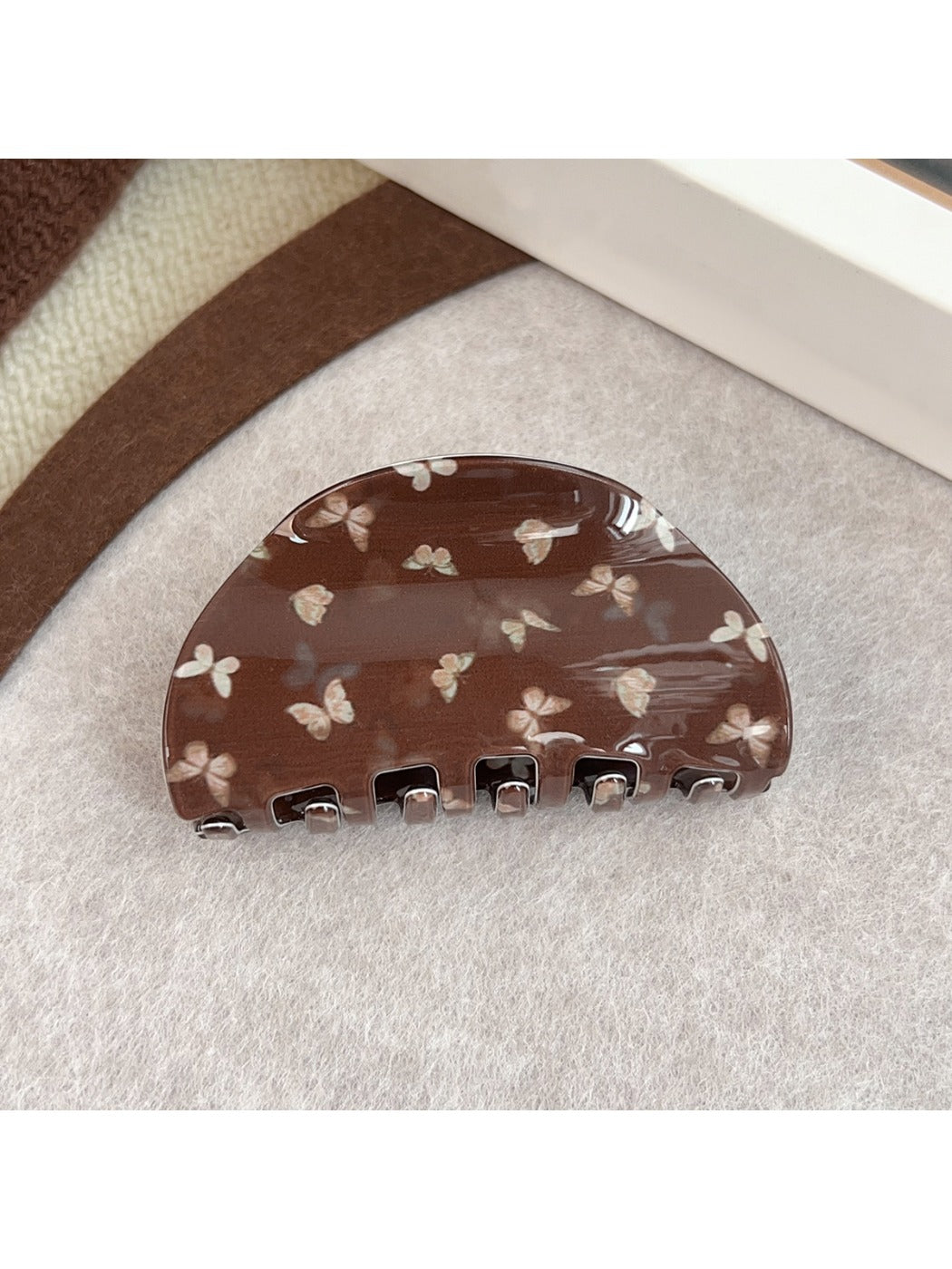 Beau claw clip resting on wooden surface with butterfly design visible