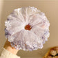 Gifty floral ruched scrunchie styled on a wrist showing fabric texture and colors