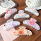 Close-up of Beau colorful flower pattern hair clip with vibrant pink and orange petals