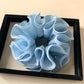 Gifty solid color ruffle scrunchie styled in a ponytail on dark hair