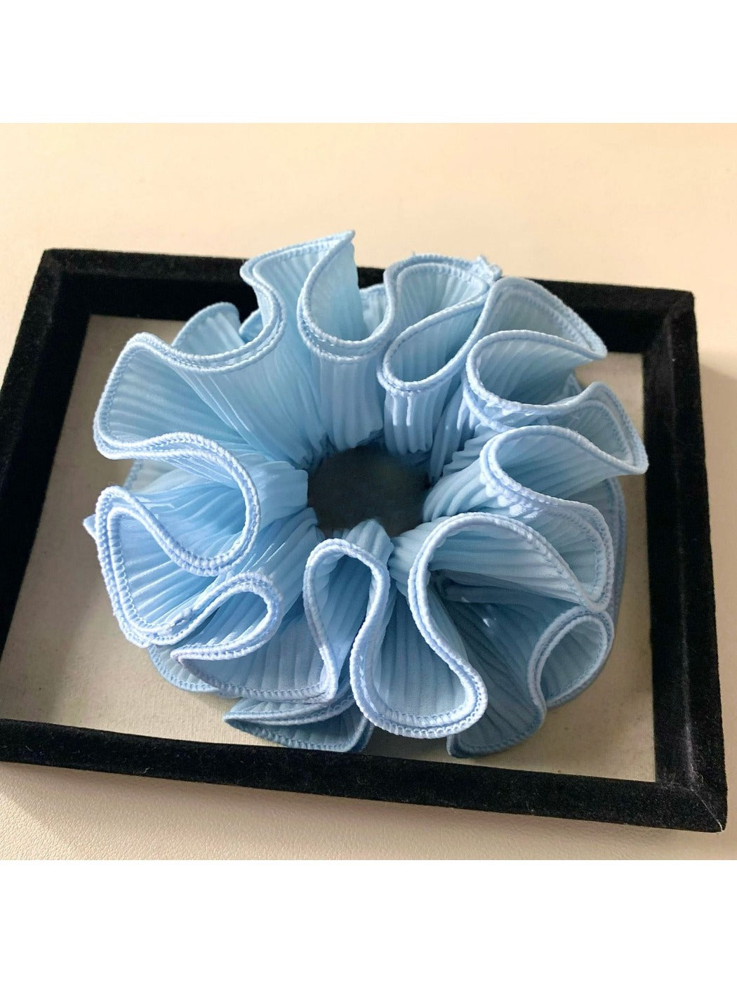 Gifty solid color ruffle scrunchie styled in a ponytail on dark hair