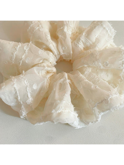 Side view of the ruffled scrunchie showing its texture and fabric folds