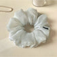 Grey ruched scrunchie displayed flat showing fabric texture and gathers