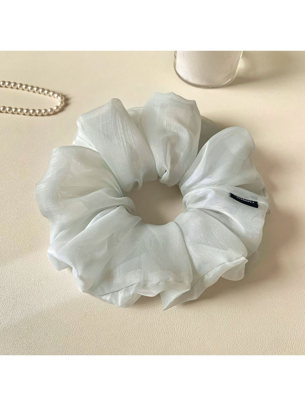 Grey ruched scrunchie displayed flat showing fabric texture and gathers