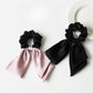 Close-up of elegant satin bow hair tie in soft pink on white background