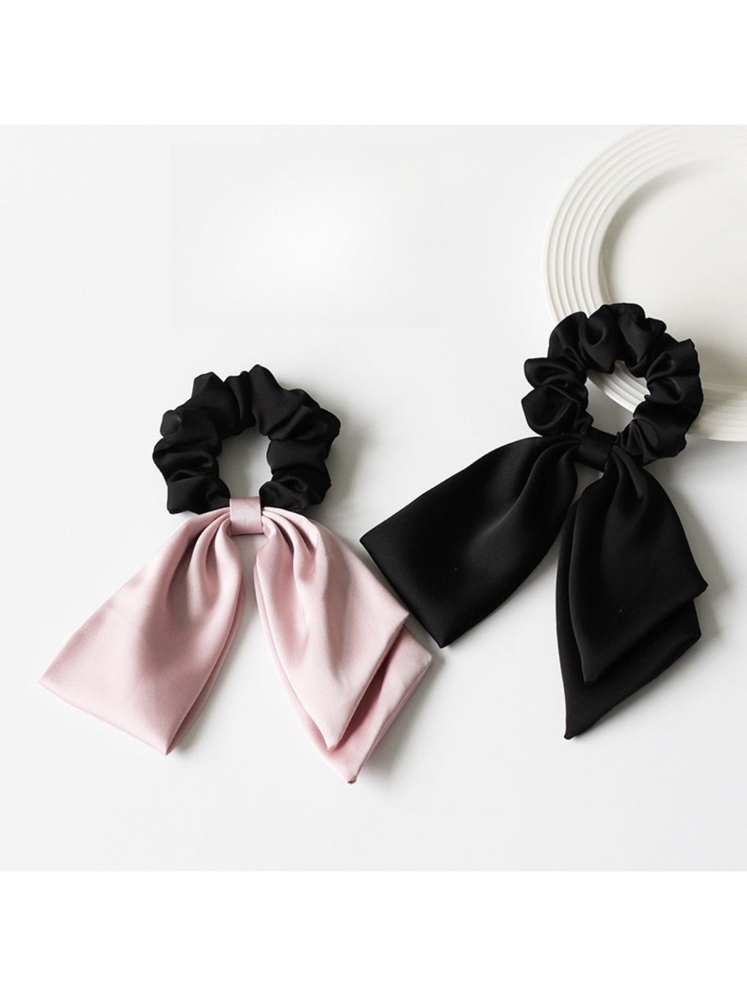 Close-up of elegant satin bow hair tie in soft pink on white background