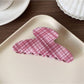 Beau pink plaid hair claw clip displayed on wooden surface