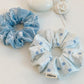 Blue bow print scrunchie displayed on a wooden surface