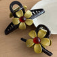Side view of beige flower-shaped claw clip highlighting the clasp mechanism