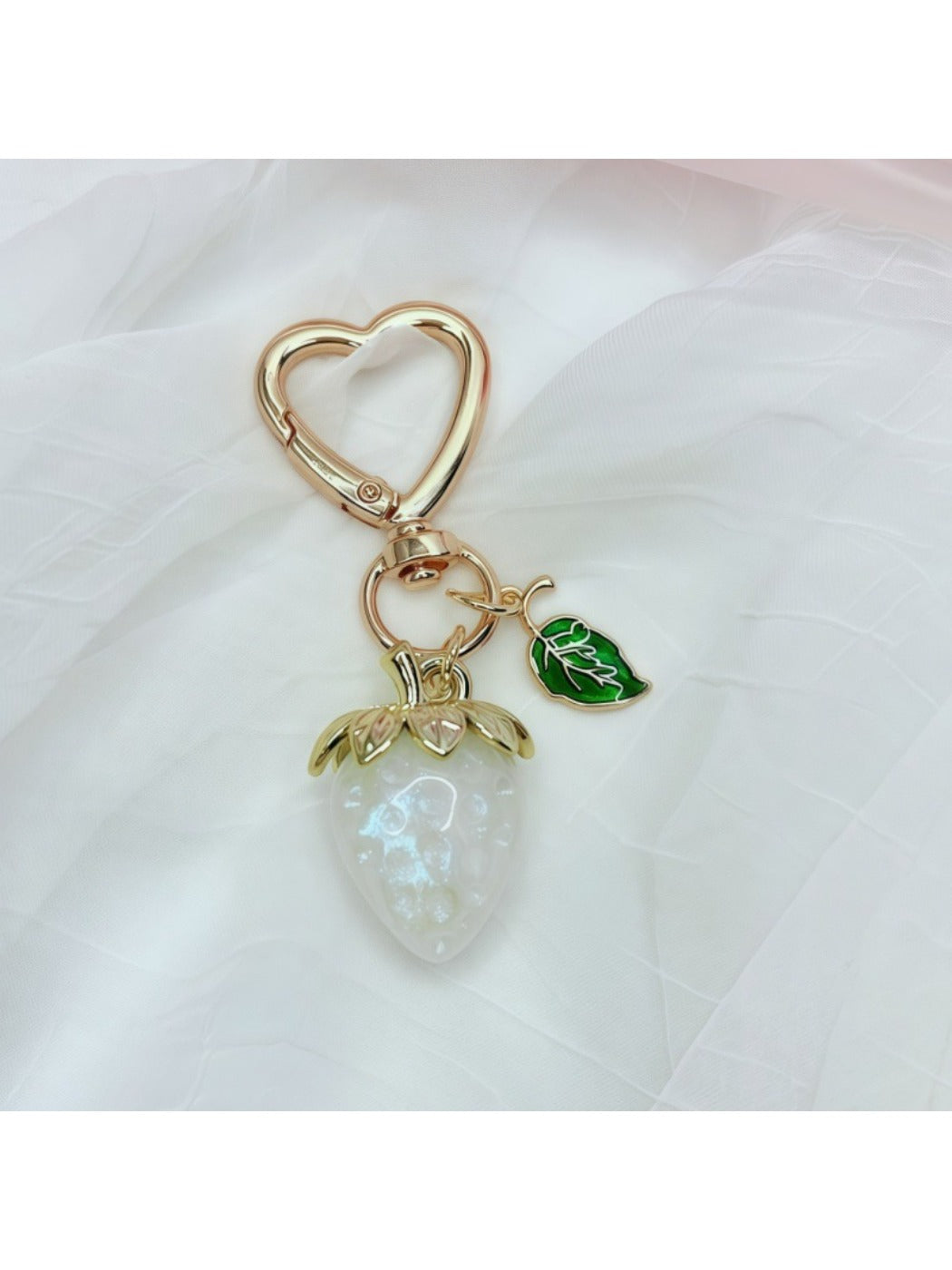 Keypus strawberry charm keychain displayed with other fruit-themed accessories