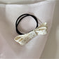 Gifty bow embellished hair tie displayed flat with elastic band visible
